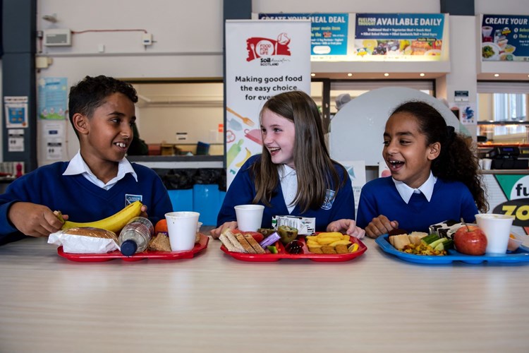 Schoolchildren talking while sitting at a table with lunch trays